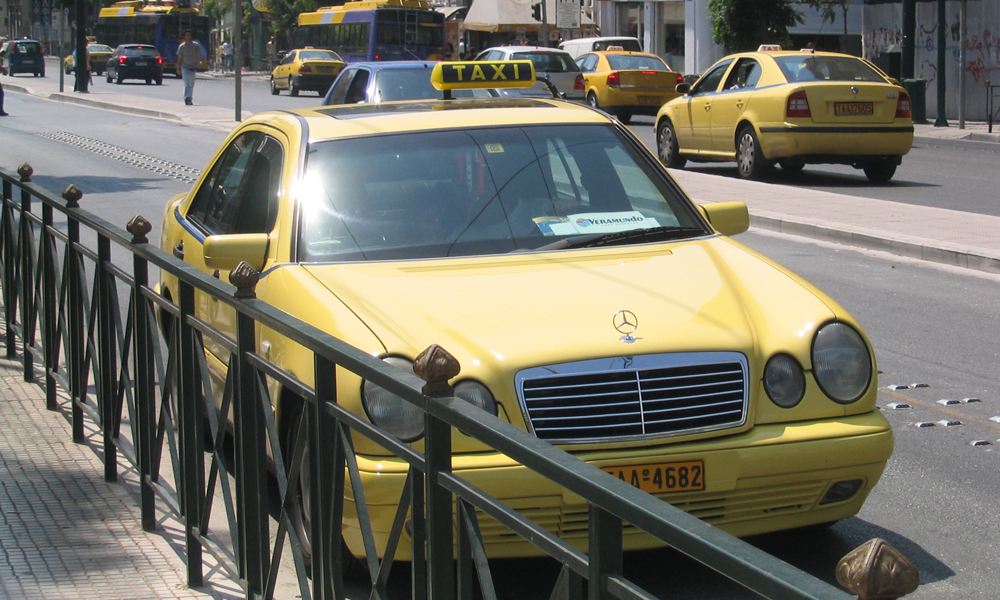 Ein gelbes Taxi hält in der griechische Stadt Athen am Straßenrand.